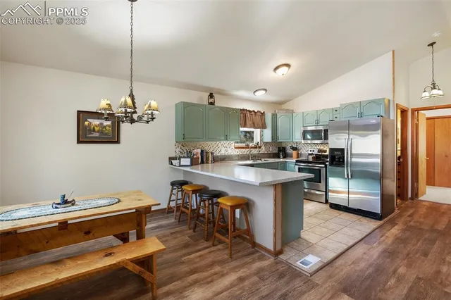 a kitchen with a refrigerator a sink dishwasher a stove and a dining table with wooden floor