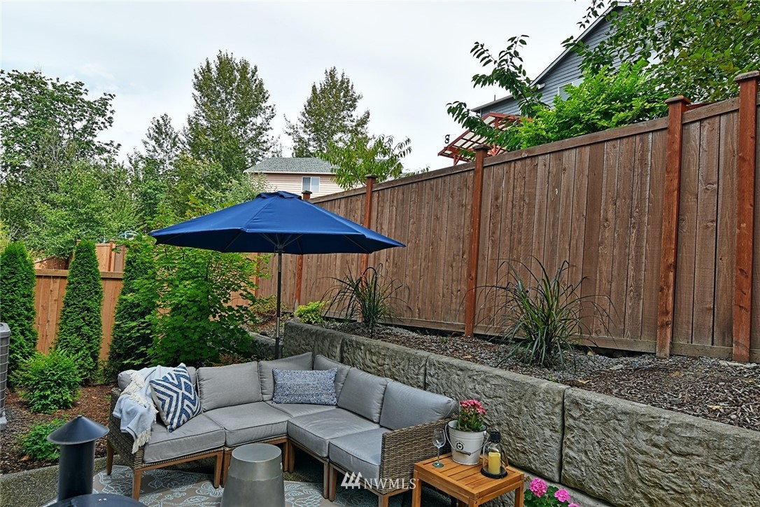 20322 85th Place Northeast Bothell, WA 98011 - Photo 24 of 24 a view of patio with couches table and chairs under an umbrella with a small yard