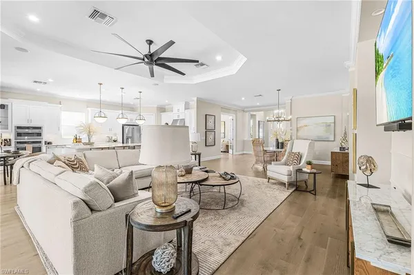 a living room with furniture kitchen view and a chandelier