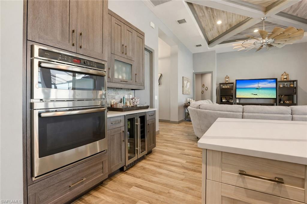 1616 Old Burnt Store Road North Cape Coral, FL 33993 - Photo 16 of 50 Kitchen featuring stainless steel double oven, coffered ceiling, wine cooler, beamed ceiling, and light wood-type flooring