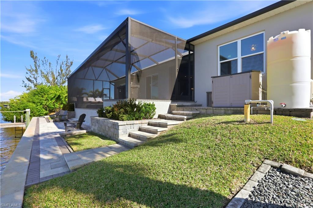 1616 Old Burnt Store Road North Cape Coral, FL 33993 - Photo 23 of 50 Rear view of property featuring a lanai, a sunroom, stucco siding, and a lawn