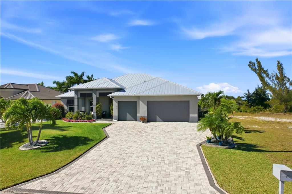 1616 Old Burnt Store Road North Cape Coral, FL 33993 - Photo 29 of 50 View of front of house with decorative driveway, a front yard, a 3 car garage and a metal roof.