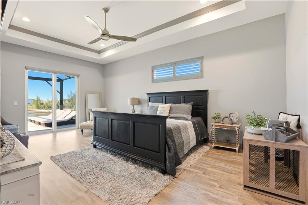 1616 Old Burnt Store Road North Cape Coral, FL 33993 - Photo 41 of 50 Primary Bedroom featuring access to outside, ceiling fan, light wood-style floors, recessed lighting, and a raised ceiling