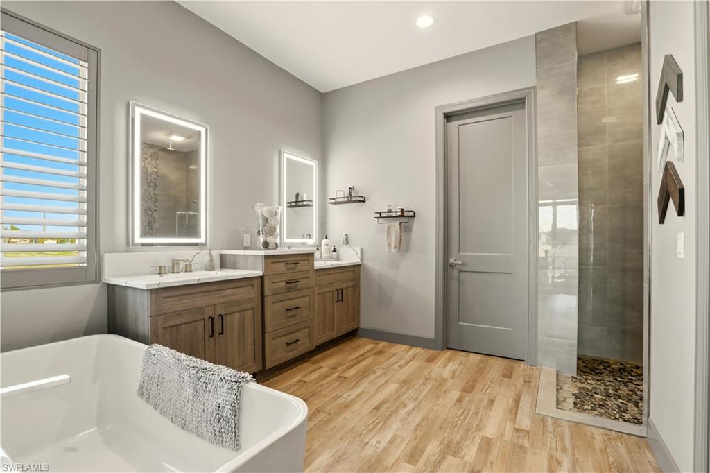 1616 Old Burnt Store Road North Cape Coral, FL 33993 - Photo 44 of 50 Primary Full bathroom featuring a walk in shower, double sink vanity, light wood-style flooring, a freestanding bath, and recessed lighting