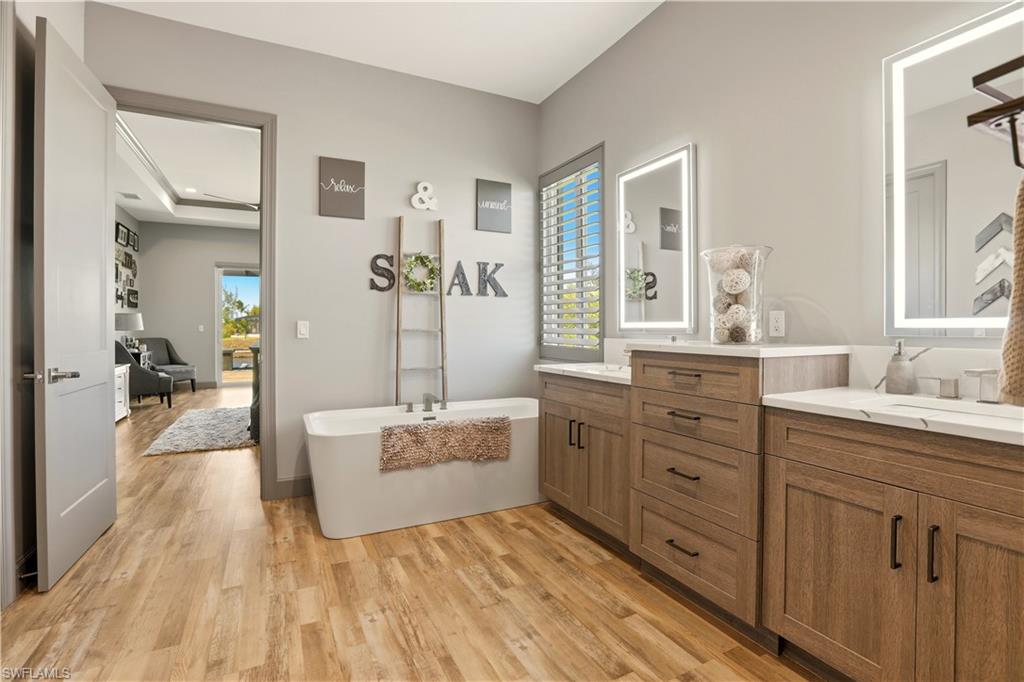 1616 Old Burnt Store Road North Cape Coral, FL 33993 - Photo 45 of 50 Primary Full bath featuring light wood-type flooring, a freestanding tub, vanity, and plenty of natural light