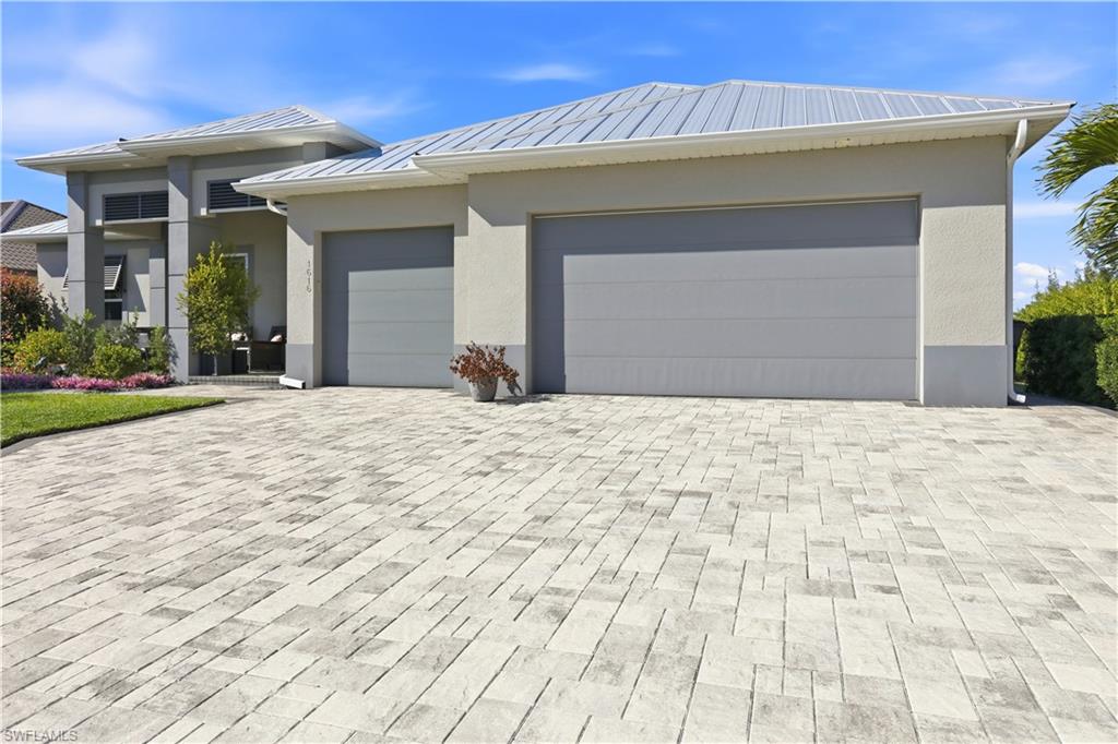 1616 Old Burnt Store Road North Cape Coral, FL 33993 - Photo 48 of 50 View of front of house featuring decorative stone driveway, a metal roof, a 3 car garage, and stucco siding