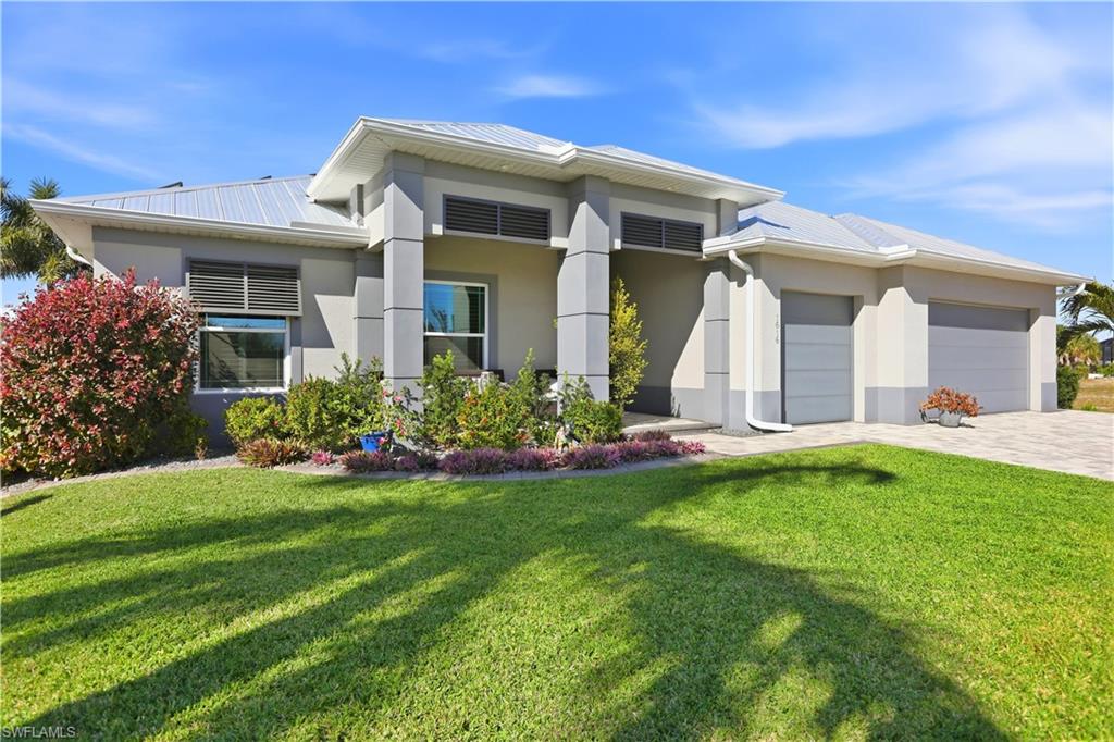 1616 Old Burnt Store Road North Cape Coral, FL 33993 - Photo 5 of 50 Front elevation with a nicely landscaped front yard, a 3 car garage, steel roof, stucco siding, and decorative driveway.