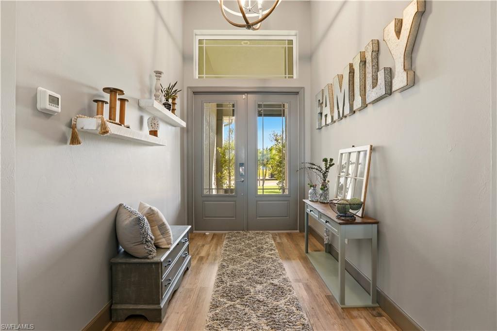 1616 Old Burnt Store Road North Cape Coral, FL 33993 - Photo 8 of 50 Doorway to outside featuring wood finished floors, french doors, a chandelier, and a towering ceiling.