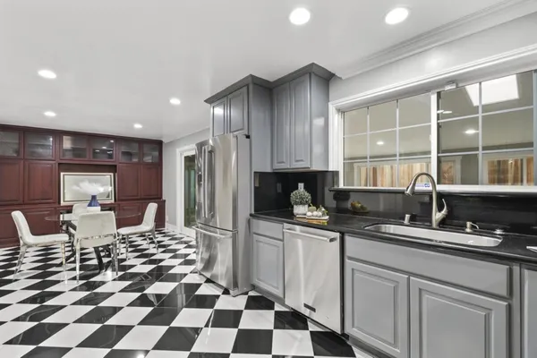 a living room with a black white checkered floor with couches and a dining table with garden view