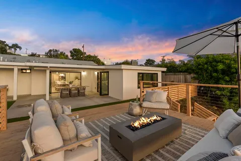 a view of a patio with couches table and chairs under an umbrella