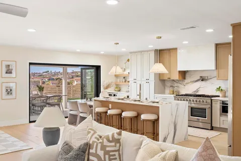 a large white kitchen with stainless steel appliances granite countertop a stove a sink dishwasher and a dining table with wooden floor