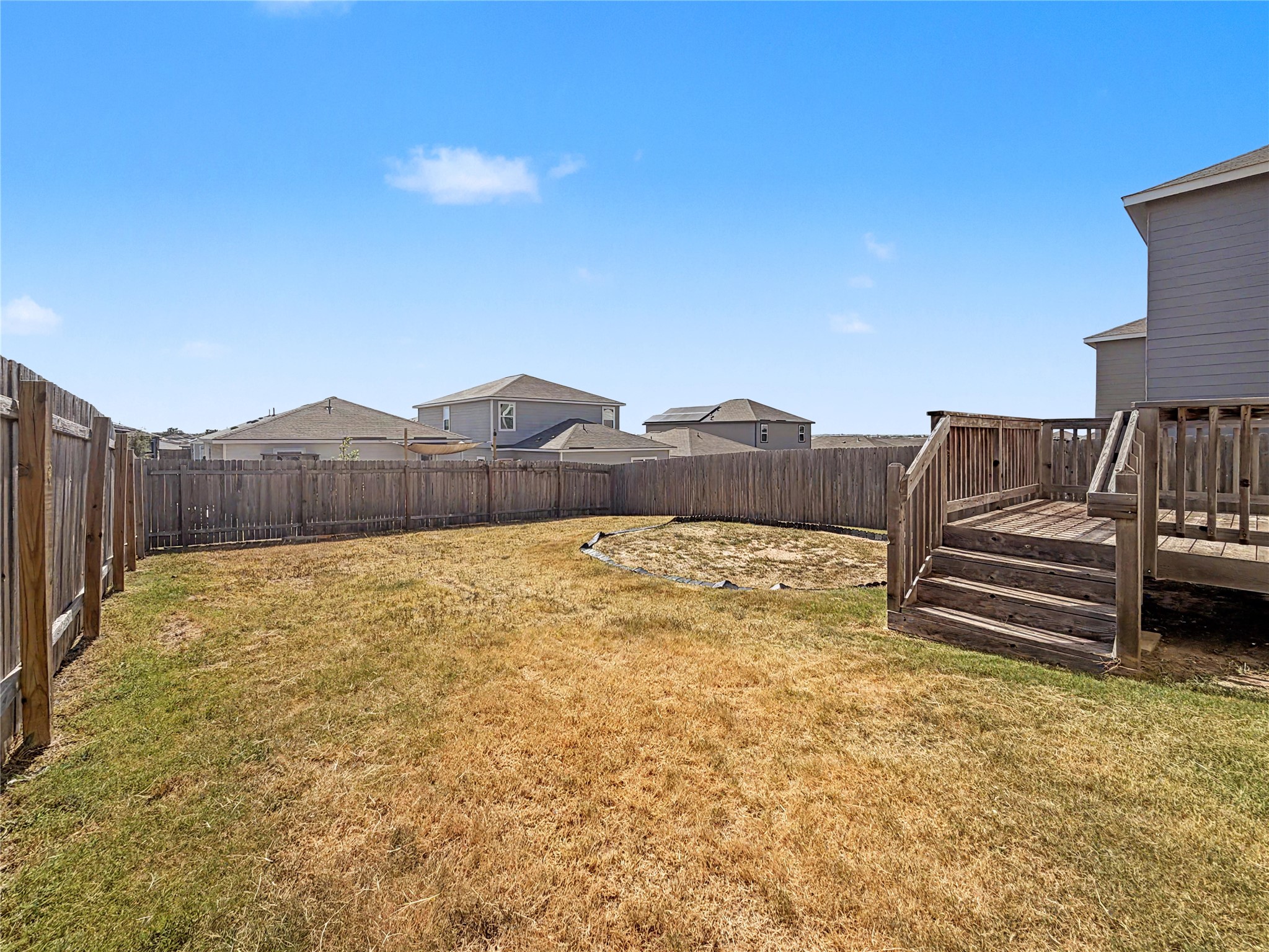 229 Night Riders Way Jarrell, TX 76537 - Photo 15 of 19 A spacious, fully fenced yard features a raised wooden deck under clear blue skies.