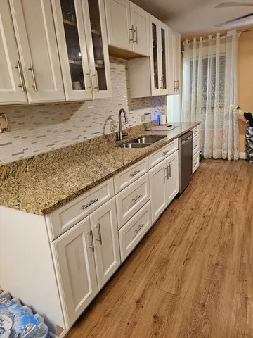 a kitchen with granite countertop white cabinets and sink