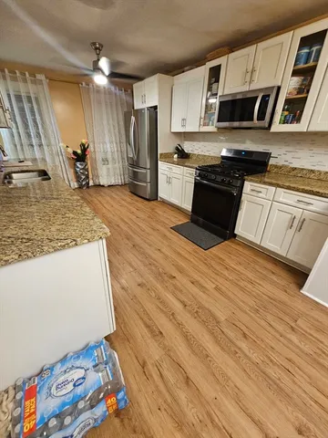 a kitchen with stainless steel appliances granite countertop a sink dishwasher stove and microwave with wooden floor