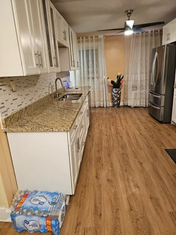 a kitchen with refrigerator and wooden floor
