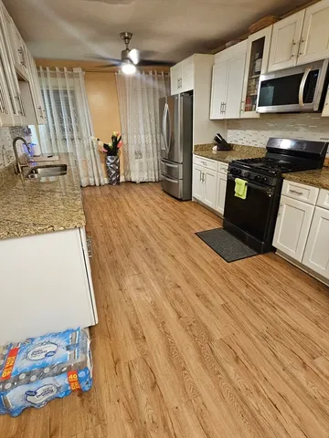 a kitchen with stainless steel appliances granite countertop a refrigerator a stove and a wooden floors