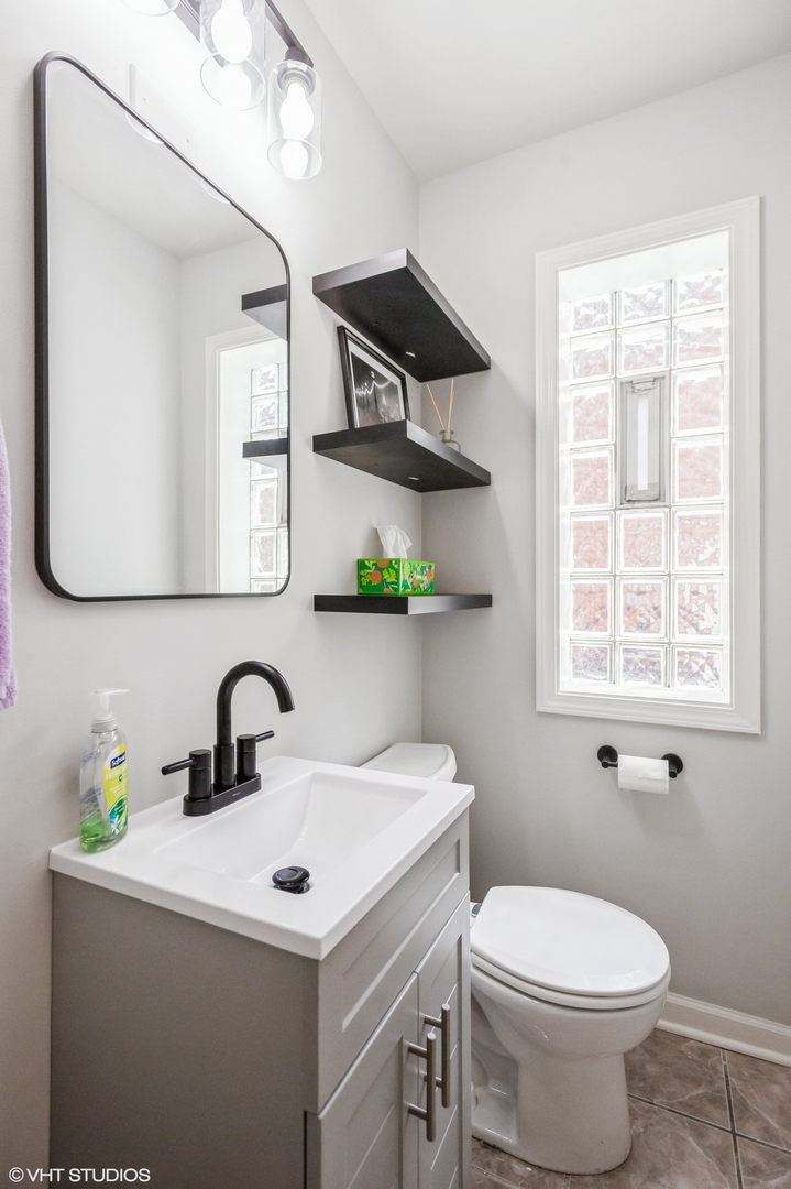 10021 Frontage Road, Unit F Skokie, IL 60077 - Photo 10 of 25 a bathroom with a sink a toilet and a mirror