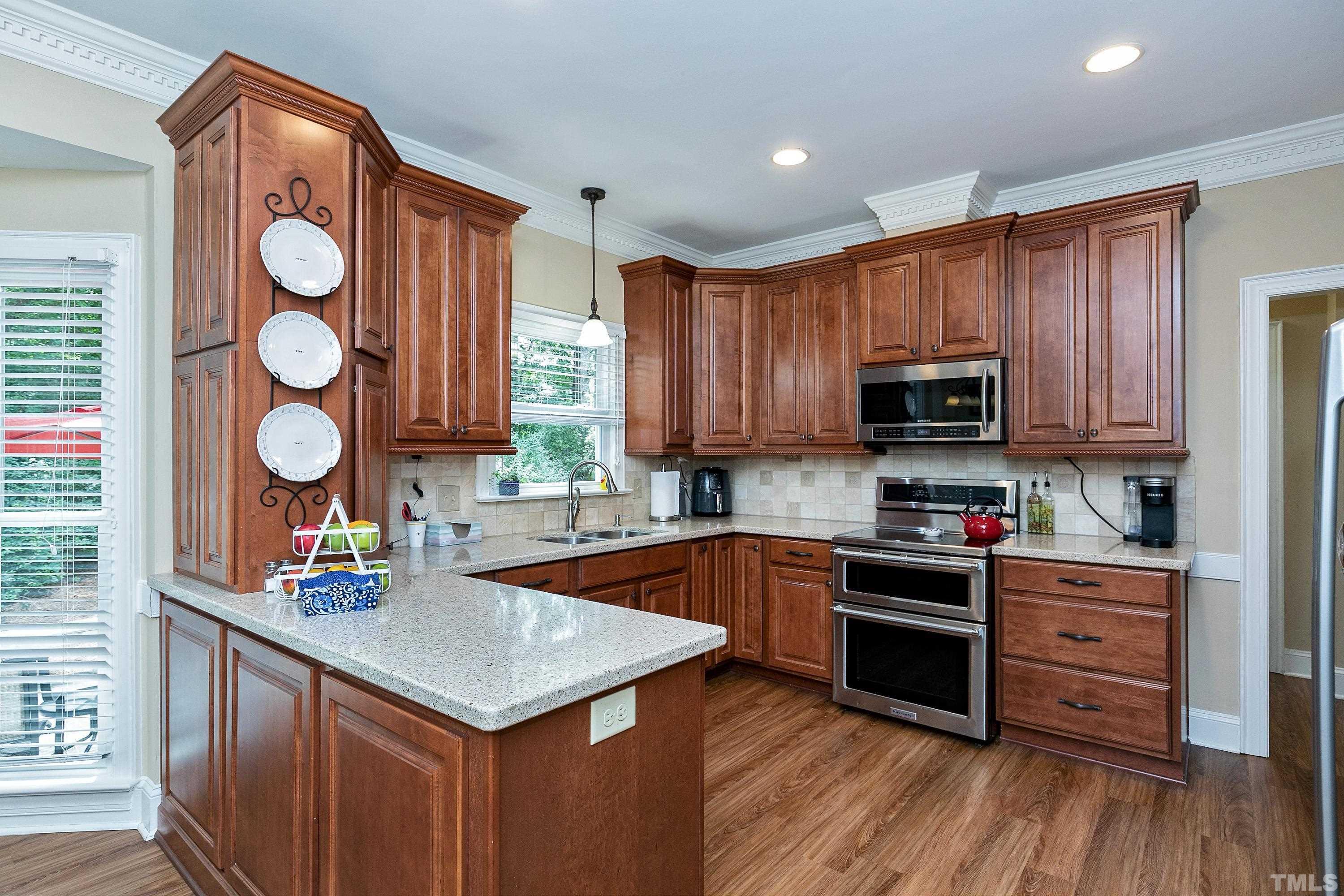 2905 Kenwick Court Raleigh, NC 27613 - Photo 13 of 45 a kitchen with stainless steel appliances granite countertop a sink dishwasher stove and wooden cabinets with wooden floor