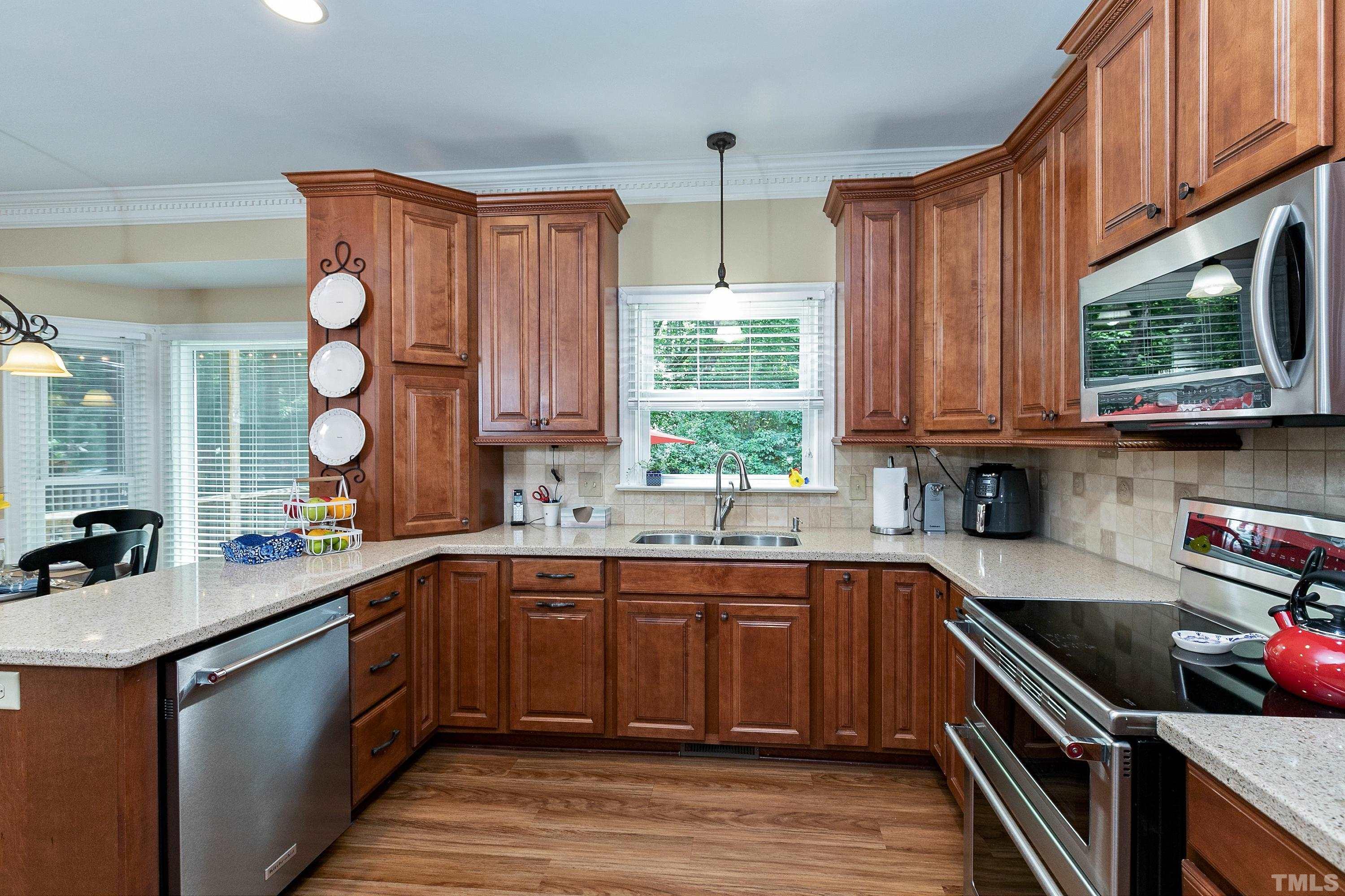 2905 Kenwick Court Raleigh, NC 27613 - Photo 15 of 45 a kitchen with stainless steel appliances wooden cabinets a sink and a stove