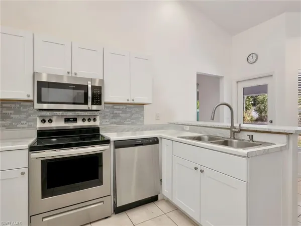 a kitchen with white cabinets and appliances