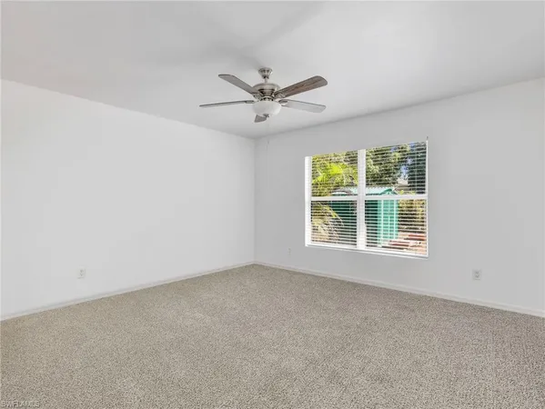 an empty room with a window and a ceiling fan