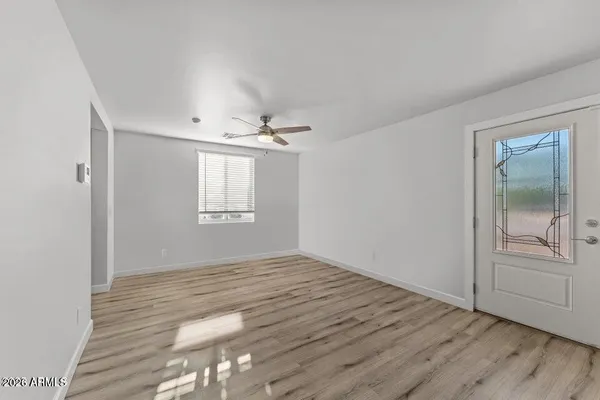 a view of an empty room with wooden floor and a window
