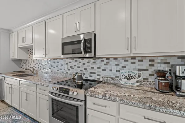 a kitchen with granite countertop white cabinets and stainless steel appliances