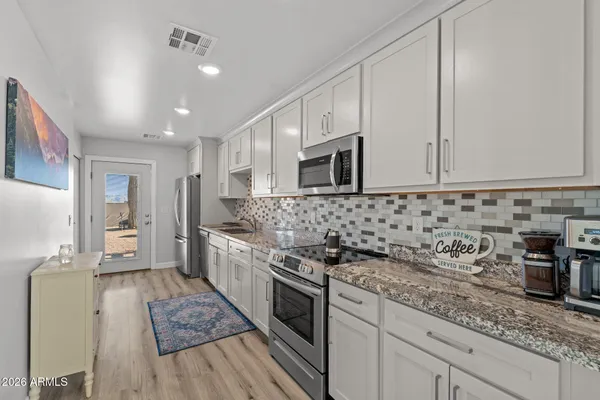 a kitchen with stainless steel appliances granite countertop a stove a sink and a microwave
