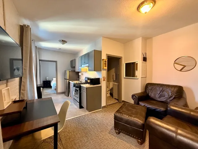 a living room with furniture kitchen view and a refrigerator