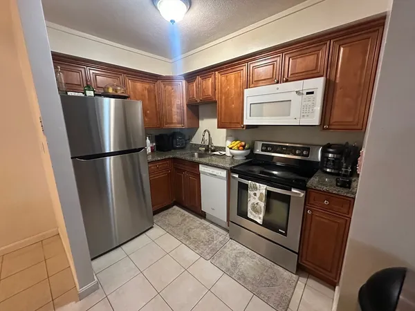 a kitchen with stainless steel appliances granite countertop a refrigerator a sink and a stove