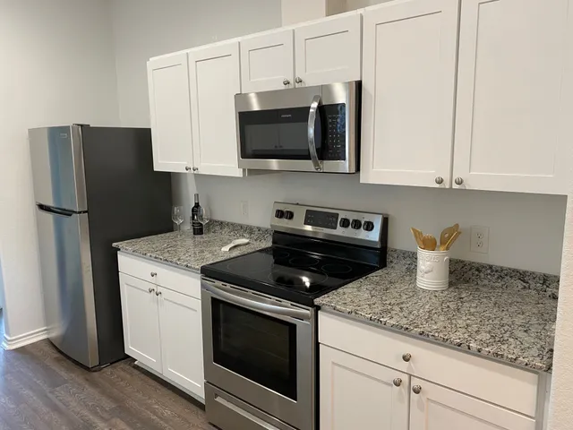 a kitchen with stainless steel appliances granite countertop a refrigerator stove and microwave