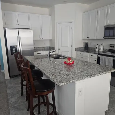 a kitchen with stainless steel appliances granite countertop a sink dishwasher a stove a refrigerator with a dining table and chairs