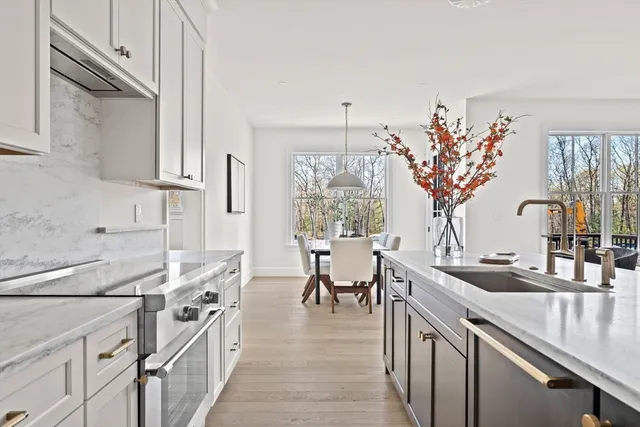 a open kitchen with stainless steel appliances granite countertop a sink dishwasher a stove a dining table and chairs with wooden floor