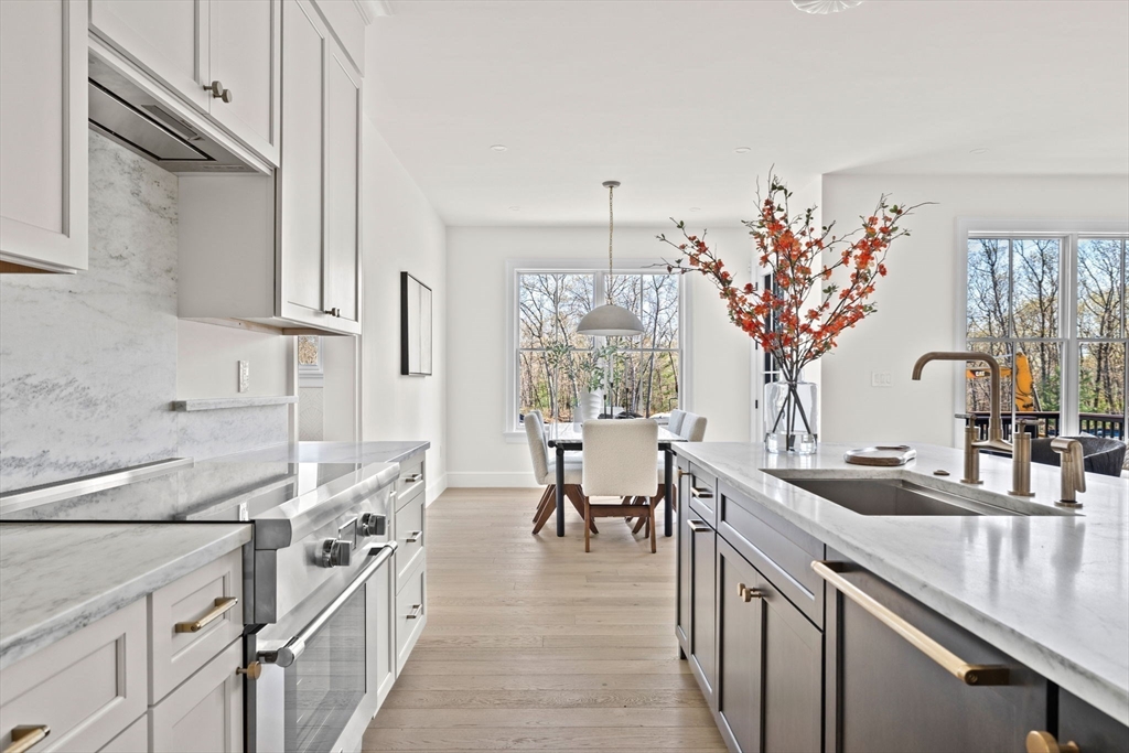 8 Common Court Lexington, MA 02421 - Photo 3 of 18 a open kitchen with stainless steel appliances granite countertop a sink dishwasher a stove a dining table and chairs with wooden floor