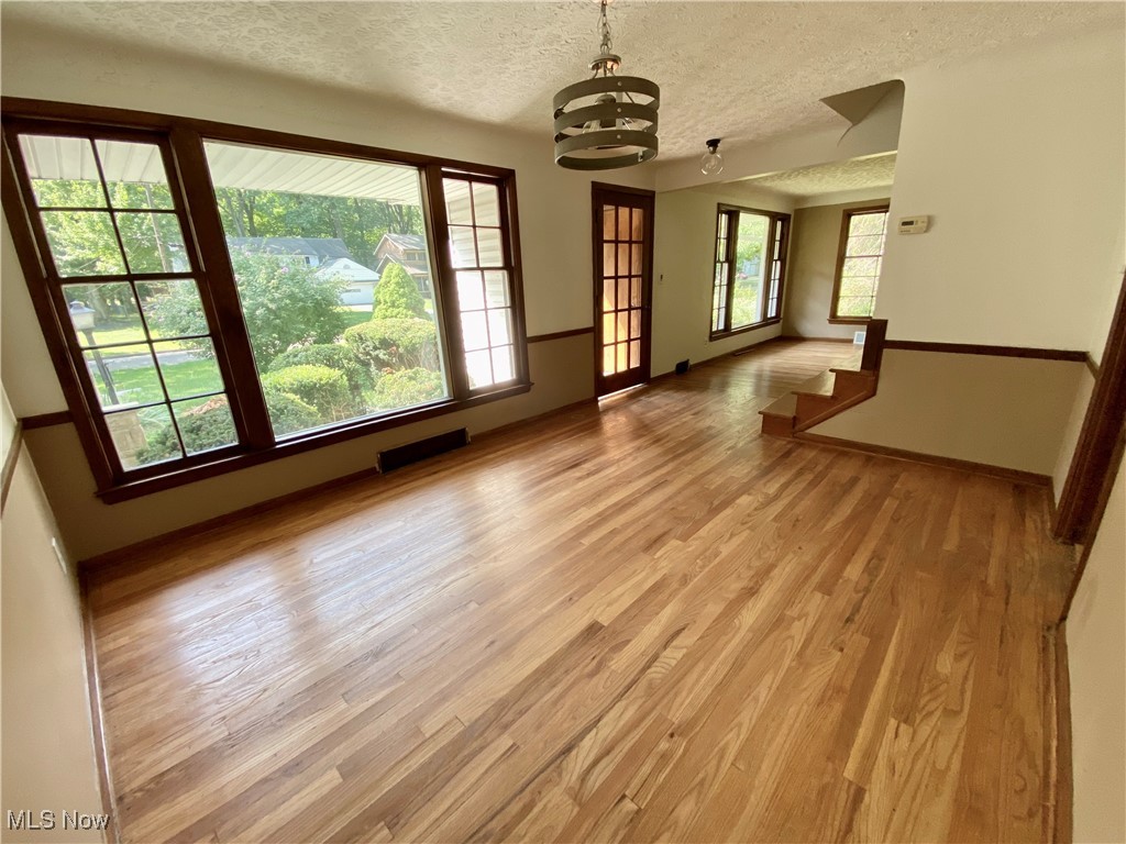 3601 Brinkmore Road Cleveland, OH 44121 - Photo 11 of 45 Unfurnished room with a textured ceiling, light hardwood / wood-style flooring, and an inviting chandelier