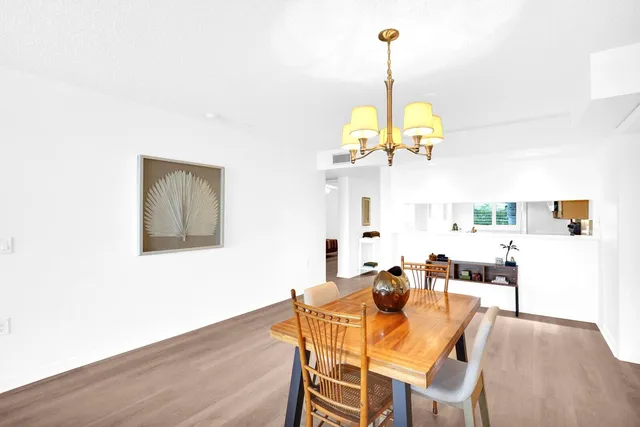 a dining room with wooden floor a chandelier a wooden table and chairs