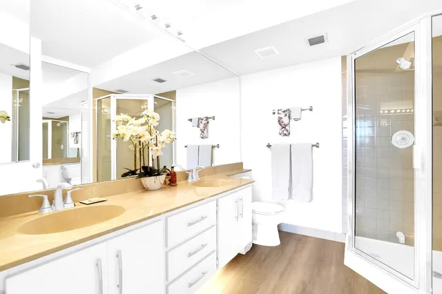 a bathroom with a granite countertop sink a toilet a mirror and shower