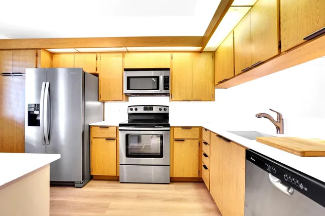 a kitchen with stainless steel appliances a stove a sink and a refrigerator
