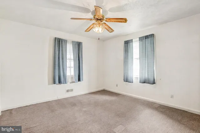 an empty room with windows and fan