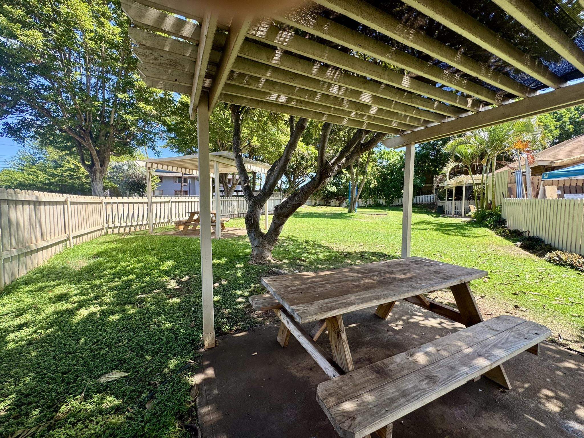 140 Uwapo Road, Unit 56204 Kihei, HI 96753 - Photo 34 of 40 a view of a backyard with table and chairs under an umbrella with a small yard