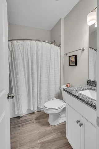 a bathroom with a granite countertop sink toilet and a mirror