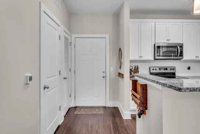 a kitchen with stainless steel appliances granite countertop a refrigerator a microwave oven a sink and dishwasher with wooden floor