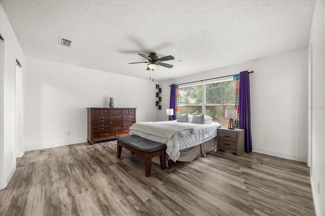 a spacious bedroom with a bed and wooden floor