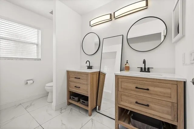 a bathroom with a granite countertop toilet a sink and a mirror