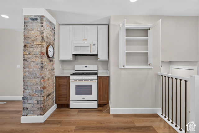 147 Center Street Clearfield, UT 84015 - Photo 32 of 55 Kitchen featuring a gas range, microwave, light-toned upper cabinetry, wood-finish flooring, and an exposed brick wall