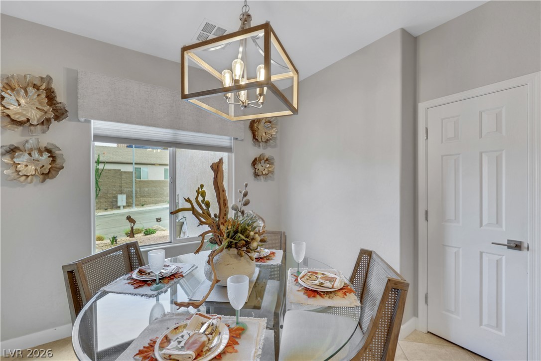 2635 Dirleton Place Henderson, NV 89044 - Photo 19 of 50 A modern dining area features tile flooring, neutral walls, and a geometric light fixture.