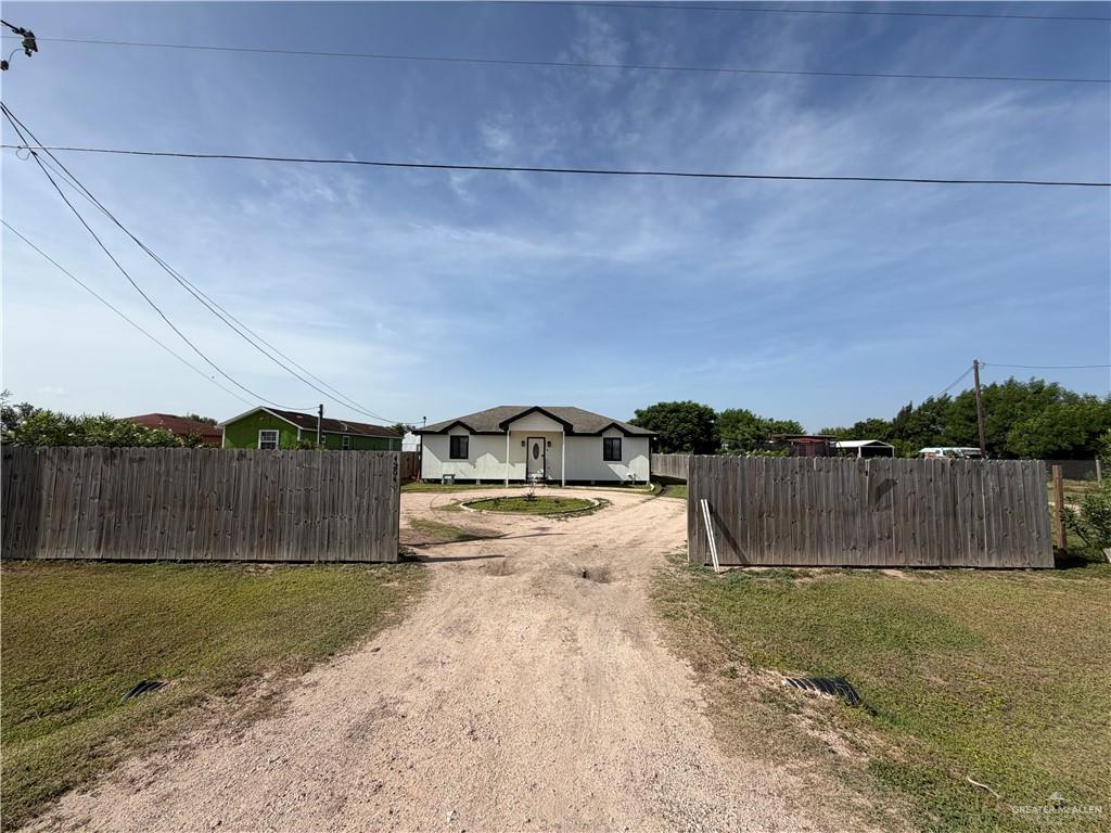 4204 Lott Road Donna, TX 78537 - Photo 28 of 28 Fenced property featuring a gravel driveway opening to a single-story residence with a white exterior, dark trim, and a prominent front door