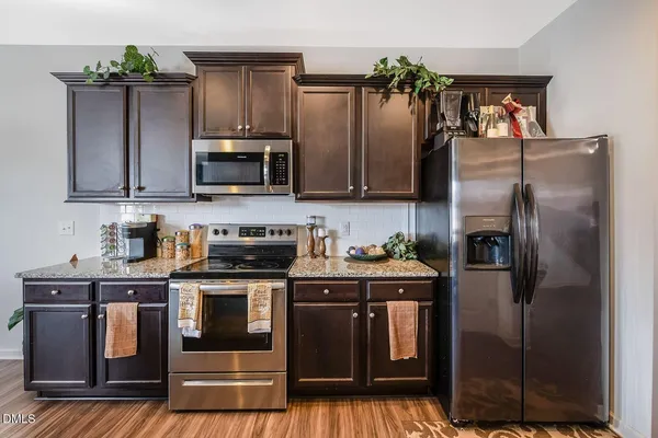 a kitchen with granite countertop a refrigerator stove and microwave