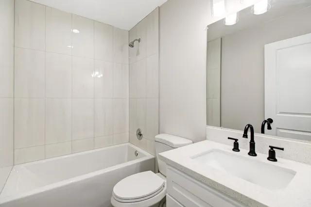 a bathroom with a bathtub shower sink vanity mirror and toilet