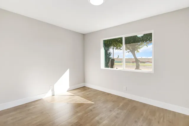 an empty room with wooden floor and windows